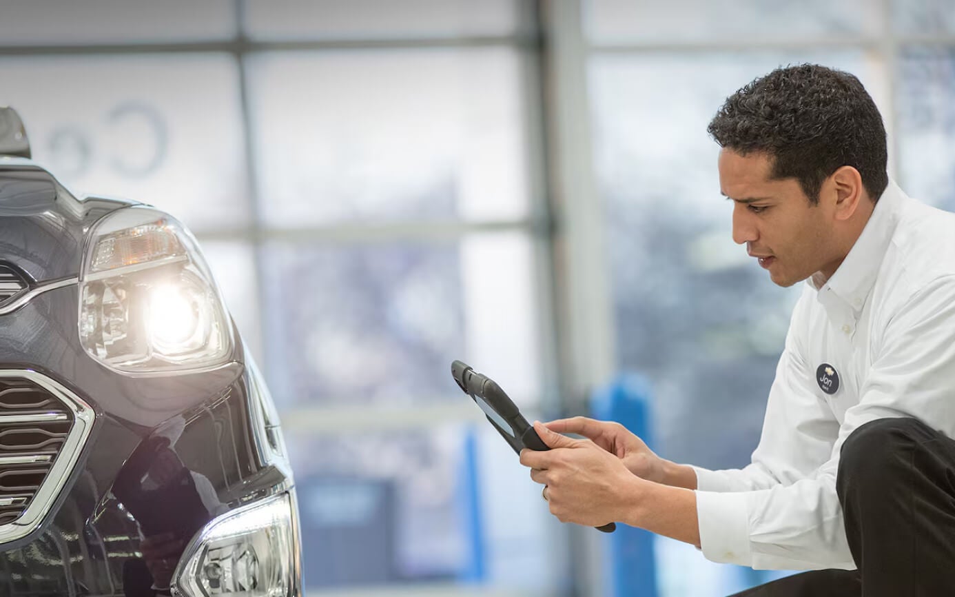 Chevrolet Equinox LT inspected by a technician using a digital tablet in a dealership service bay.