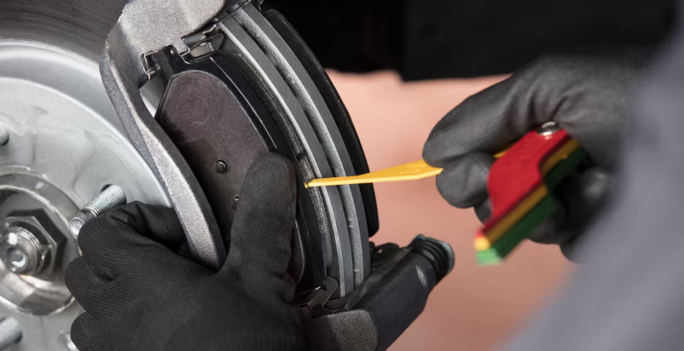 Chevrolet mechanic performing a brake inspection during routine maintenance.