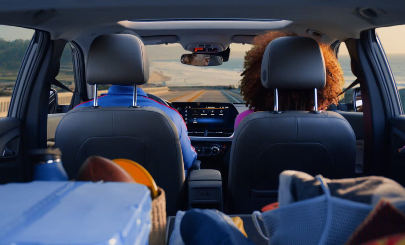 Interior of 2026 Chevy Trax; backseat POV viewing forward towards dash and the open road beyond.